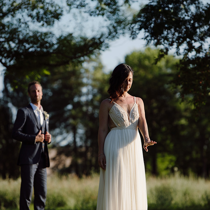Sposa nel giardino del ristorante Le Case di Macerata mentre osserva la sua fede, con lo sposo accanto a lei in un momento intimo e romantico.