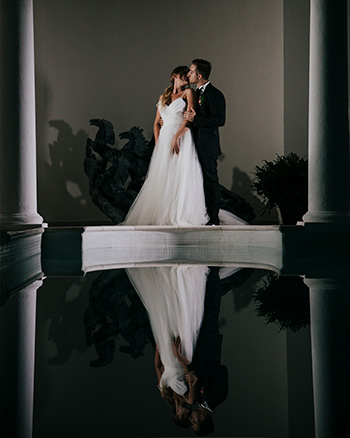 Gli sposi si scambiano un bacio avvolti dall’atmosfera intima della spa di Le Case di Macerata, tra luci soffuse e riflessi eleganti.